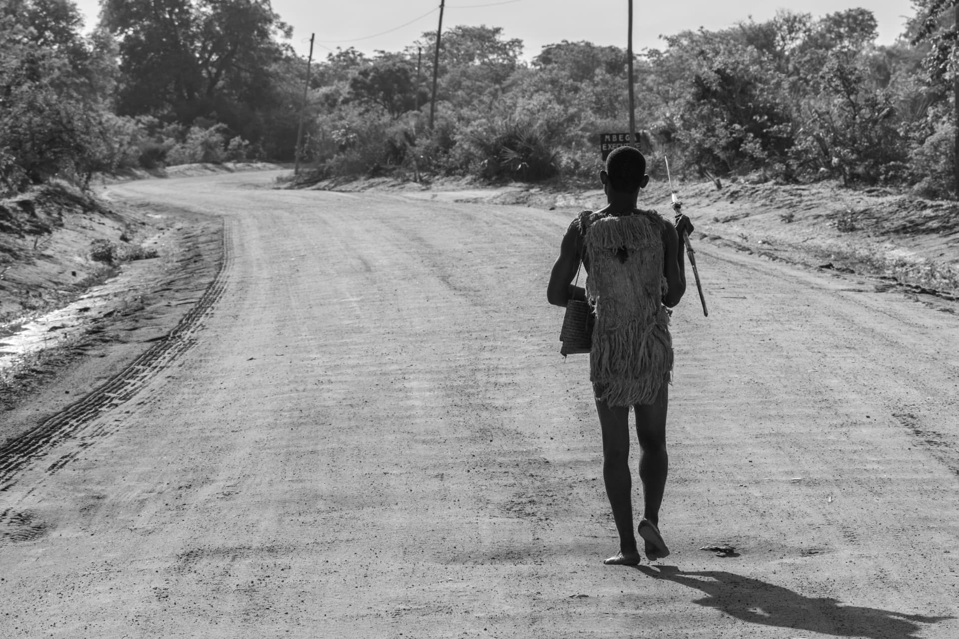 A lone figure walking along a dusty road through rural Tanzania