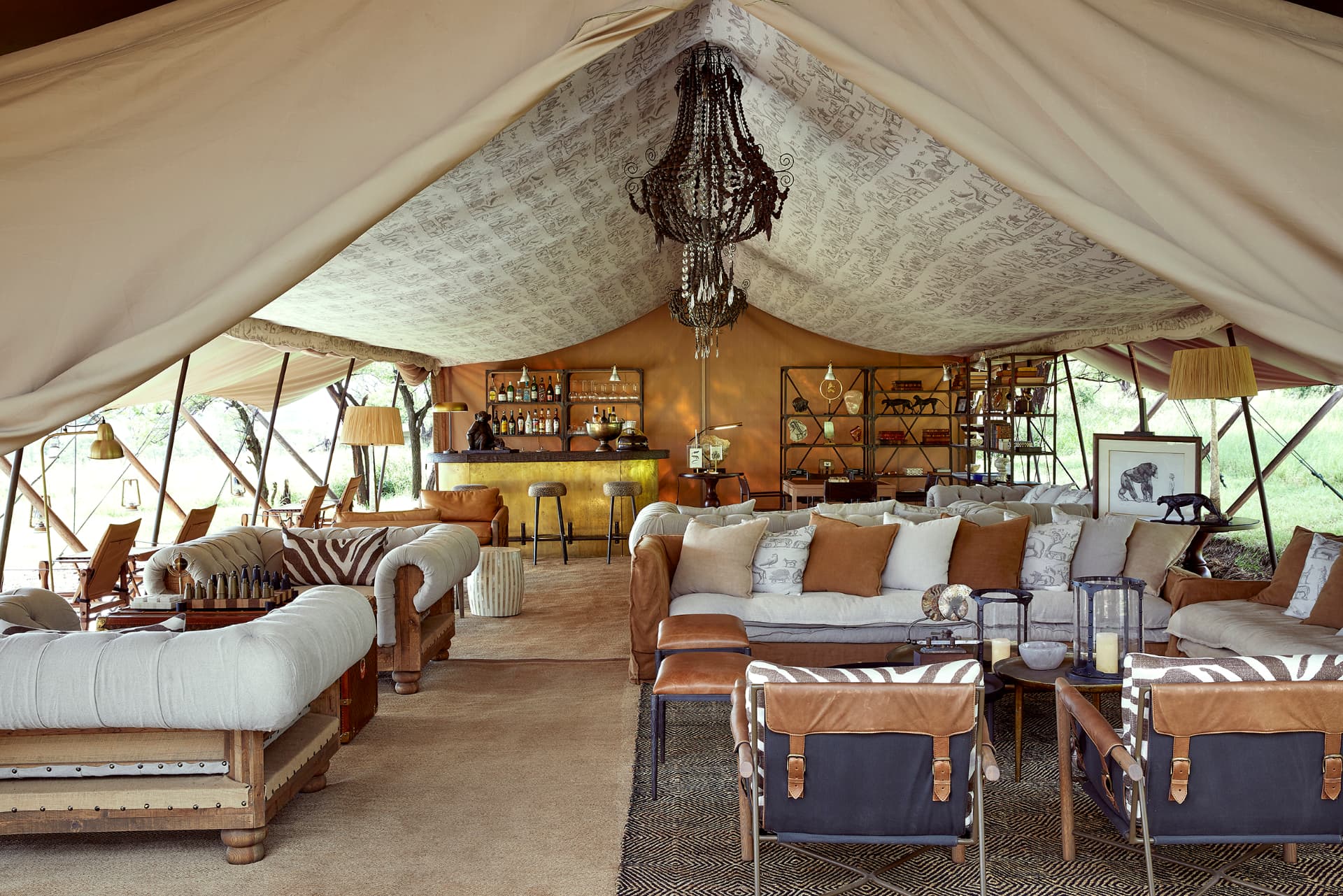 Closed while relocating: Apr 1–May 14, Jul 1–9, Nov 20–Dec 9. Laba Migration Camp lounge tent, chesterfield sofas, safari chairs, beaded chandelier and brass bar open to the North Serengeti bush