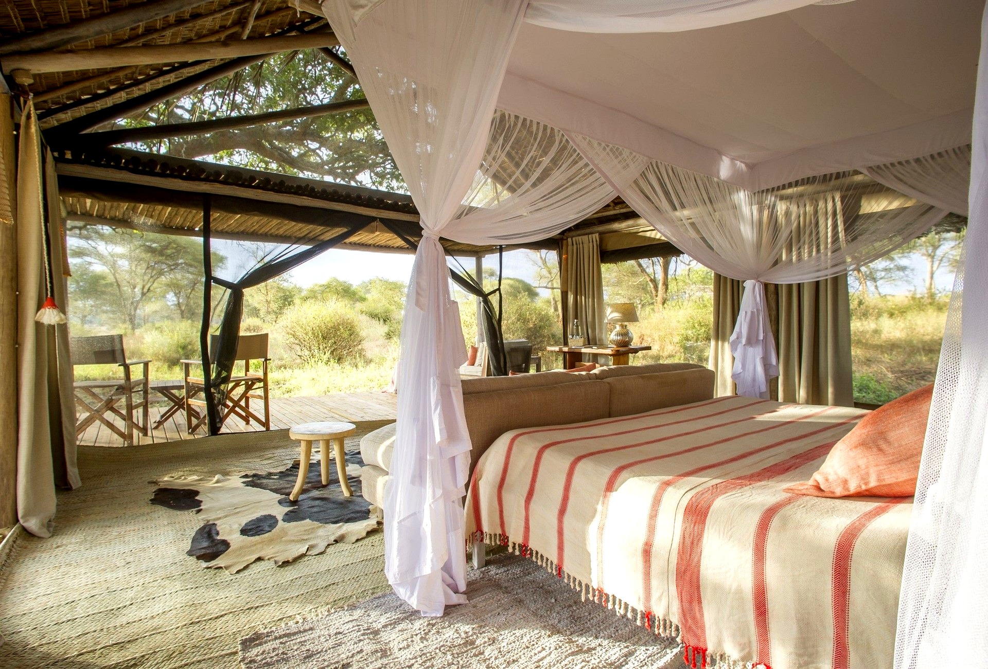 Closed: Mar 18–May 31. Kuro safari tent interior with four-poster bed, mosquito nets, deck chairs and open views over the Tarangire bush