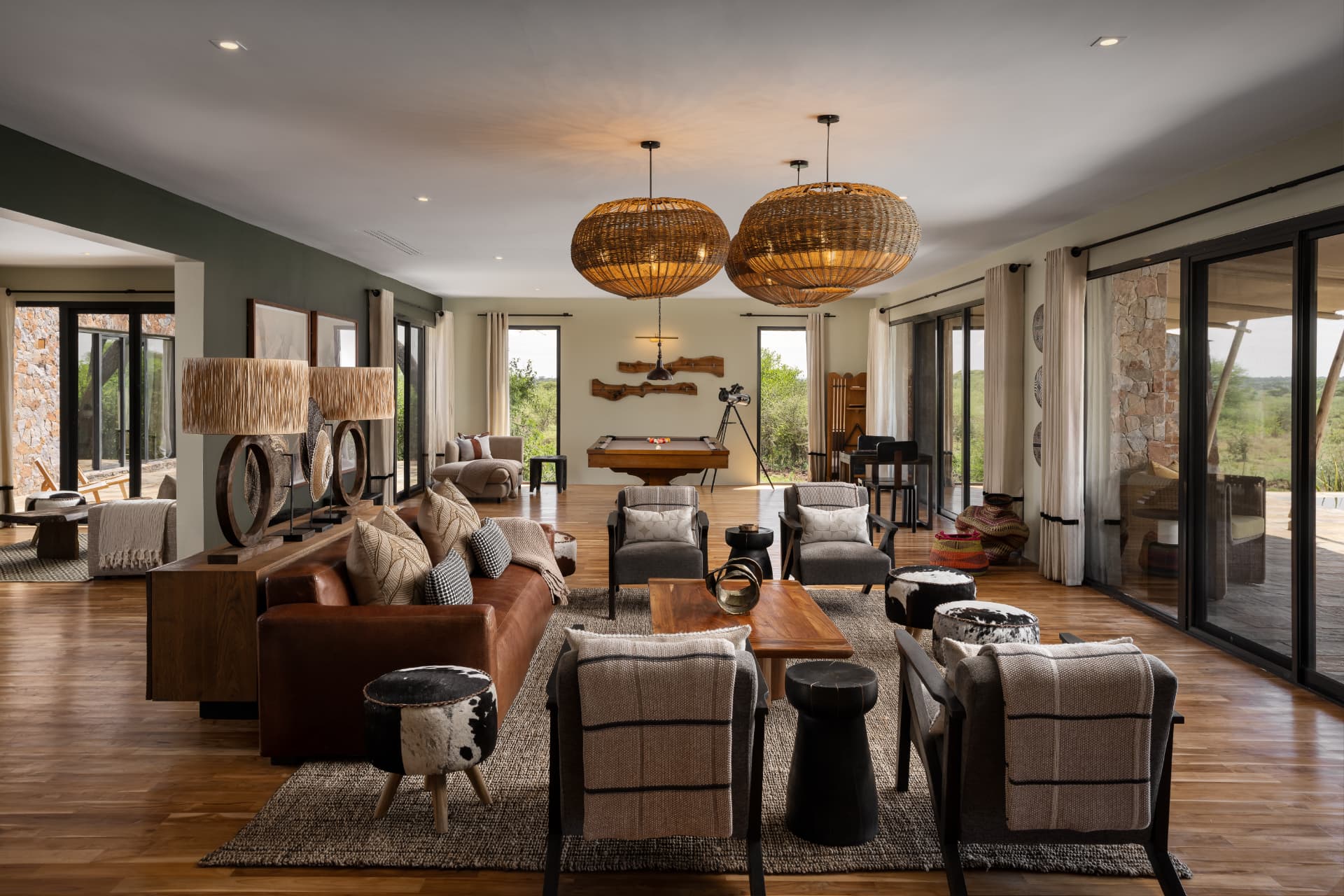 Mapito Safari Camp villa lounge, woven pendant lamps, leather sofas, billiard table and floor-to-ceiling views over the Serengeti