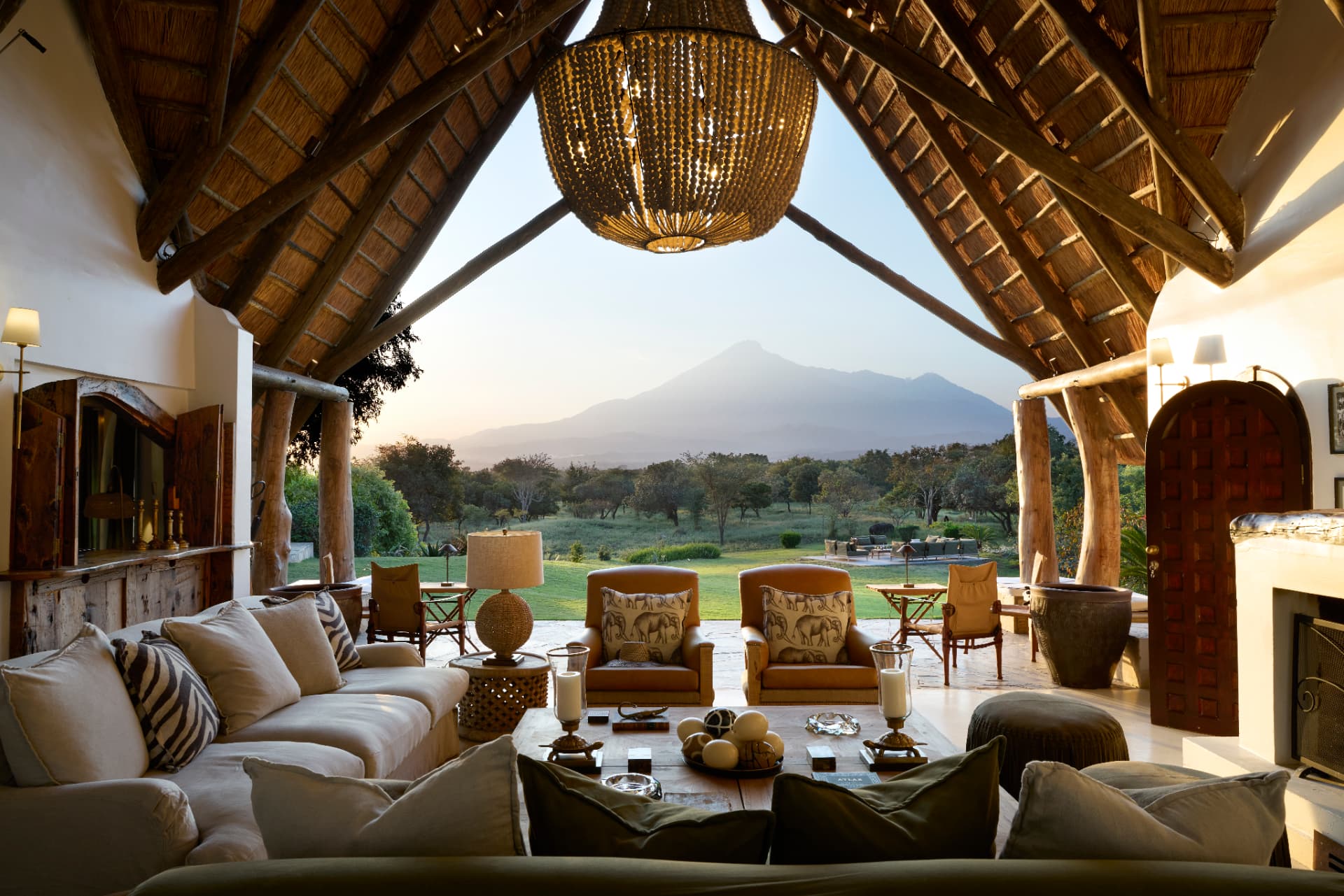 Laba Mama Simba main lounge with thatched roof, chandelier, sofas and Mount Meru view near Arusha, Tanzania