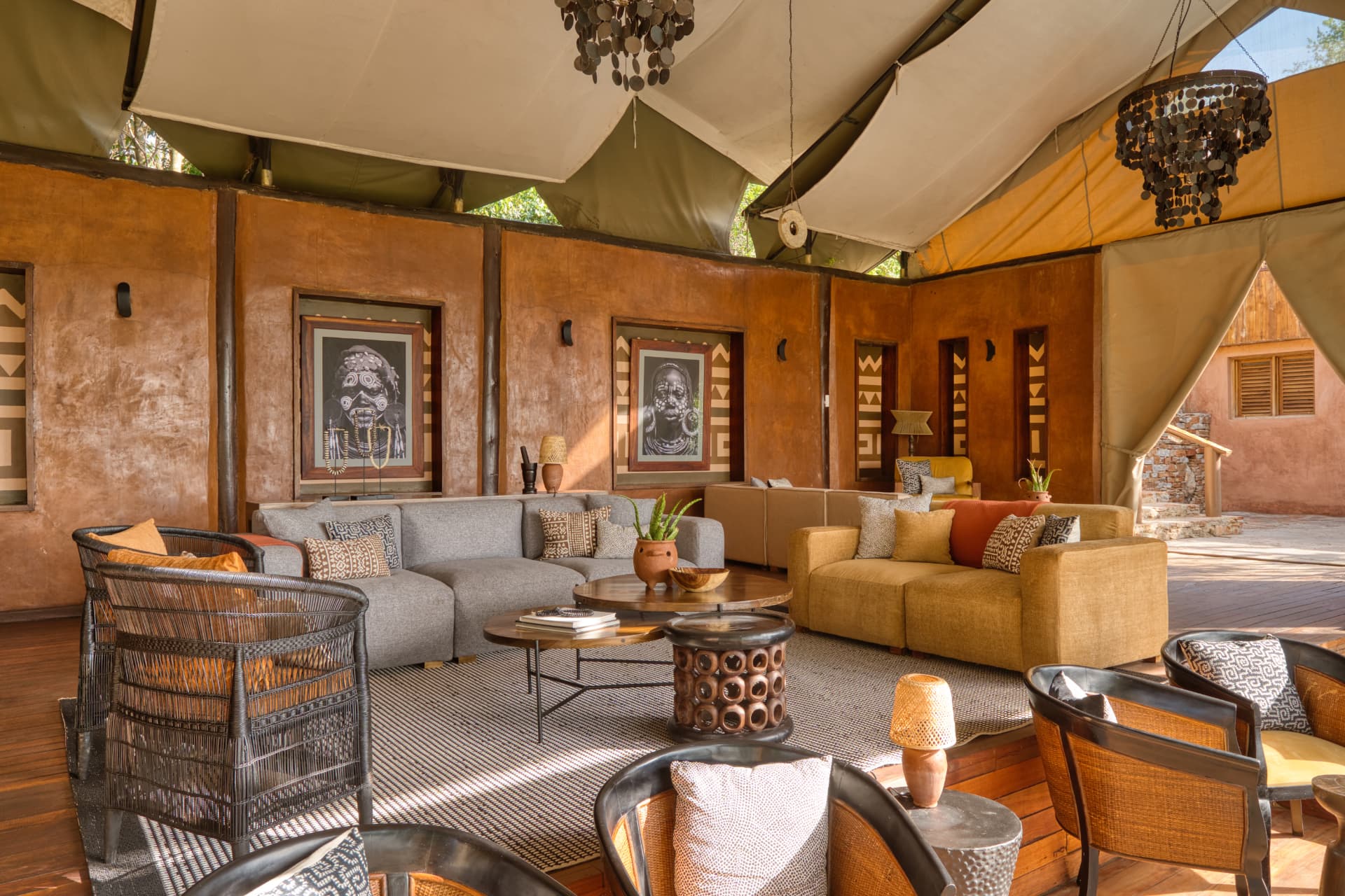 Serengeti Migration Camp lounge interior, woven chandeliers, ochre sofas, tribal artwork and open canvas tent with views to the bush