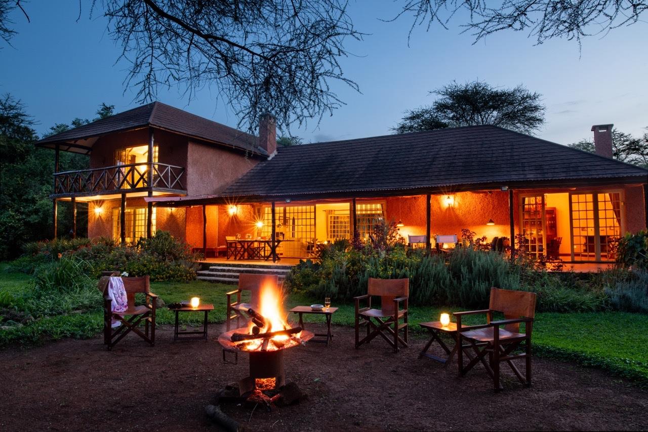 Kili Villa main house at dusk, illuminated terrace and swimming pool near Arusha, Tanzania